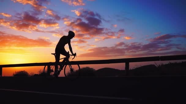 Silueta de un ciclista al atardecer en las montañas — Vídeo de stock