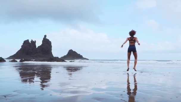 Skok Squats - Dopasuj Kobieta nogi szkolenia z treningu hiit skoki ćwiczenia przysiady. Trening fitness robi ćwiczenia cardio na lato ocean biały piasek plaży robi wybuchowe skoki wobec przyśpieszyć nasycić. — Wideo stockowe