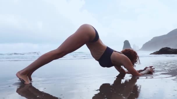 Cvičení jógy při západu slunce. Yong žena dělá cvičení jógy na krásné pláži.