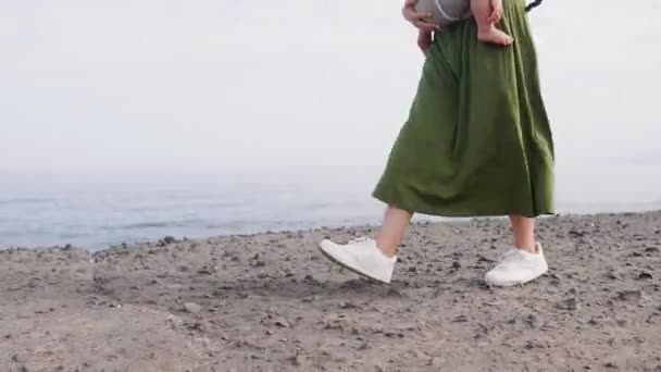 Baby en moeder op zee bij zomerdag. Wandelen op de natuur buiten en gelukkige familie. Kind in de rugzak van een vervoerder. Vrouw en haar baby op oceaan van de kust op het eiland Tenerife, Spanje. Reizen Europa — Stockvideo