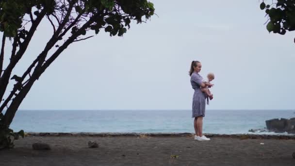 Toegewijde moeder en baby knuffelen, hechting kwaliteitstijd observeren van heldere blauwe cloudscape doorbrengen. Attente ouderschap en familie lifestyle concept. Natuur en mensen achtergrond. — Stockvideo