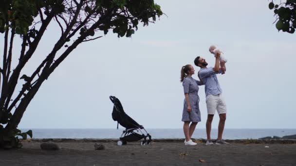 Babyjongen leunt over zijn schouder vaders speels neus aanraken met zijn prachtige lachende moeder — Stockvideo