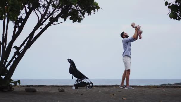 Pappa med en baby på stranden med en barnvagn — Stockvideo