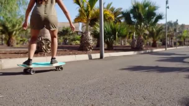 Giovane ragazza cavalca su strada vicino a palme sul longboard al rallentatore — Video Stock