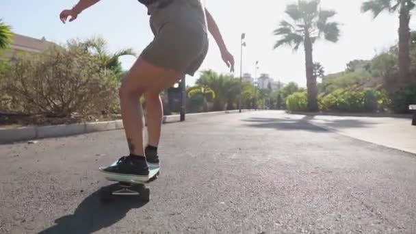 Meisje op een skateboard in korte broek ritten op de weg langs het strand en palm bomen — Stockvideo