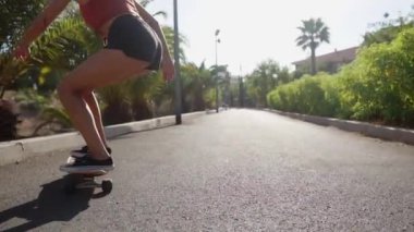 Kısacası bir kaykay üzerinde kız rides plaj ve palmiye ağaçları boyunca yolda şort