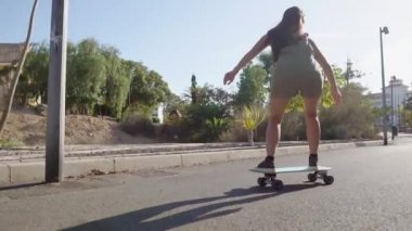 Island girl longboard üzerinde yaz kısa şort plaj ve palmiye ağaçları yakınındaki yolda rides