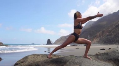 Sportif bir kadın meditasyon ve yoga yaparken ve doğa ile denge içinde olmak bir çalışmadan sonra kasları uzanıyor. Kanarya Adaları Tenerife