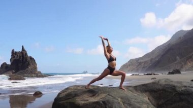 Sportif bir kadın meditasyon ve yoga yaparken ve doğa ile denge içinde olmak bir çalışmadan sonra kasları uzanıyor. Kanarya Adaları Tenerife