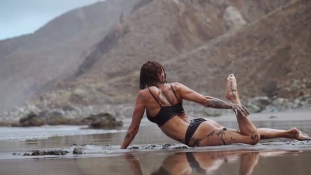 Gyönyörű nő fürdőruha tánc közben a fekete homokos strand közelében az óceán, Kanári-szigetek Tenerife — Stock videók