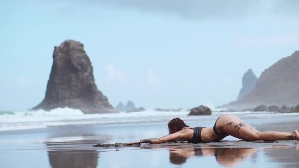 Gyönyörű nő fürdőruha tánc közben a fekete homokos strand közelében az óceán, Kanári-szigetek Tenerife — Stock videók