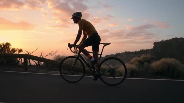 Un jeune sportif en vélo sur une serpentine de montagne avec un casque de t-shirt jaune et un équipement sportif vue arrière. Steadicam au ralenti — Video