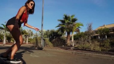 Palmiye ağaçları boyunca plaja yakın bir parkta bir gemide şort ve güneş gözlüğü güzel kız rides