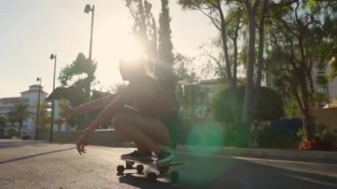 Şort ve spor ayakkabısı palmiye ağaçlarında yakınındaki bir longboard sürme yaz aylarında genç bir kadın