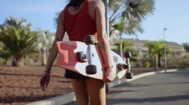 İki kız paten kurulu Park palmiye ağaçları ve kum ile yol boyunca için komiteler ile günbatımı gülümseyen yürümek