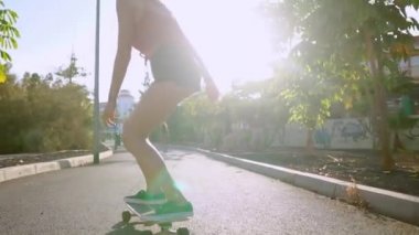 Kız yavaş çekimde bir kaykay Park palmiye ağaçları ile sürmek