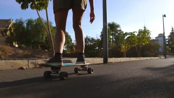 Девушка в замедленной съемке катается на скейтборде в парке с пальмами — стоковое видео