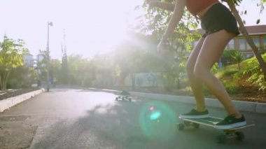 İki kadın arkadaş kaykaylar sürmek yokuş aşağı resort taşıma ve gülümseyen eğleniyor. Yol boyunca palmiye ağaçları