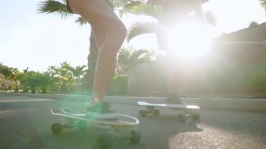Genç İspanyol kız güneşin ışınları yavaş çekimde parkta yollarının asfalt palmiye ağaçlarının yanında bir adada kaykaylar binmek. Mutluluk ve sağlıklı yaşam..