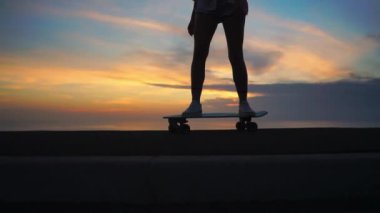 Ağır çekim steadicam çekimde günbatımı gökyüzü karşı bir kaykaycı silüeti
