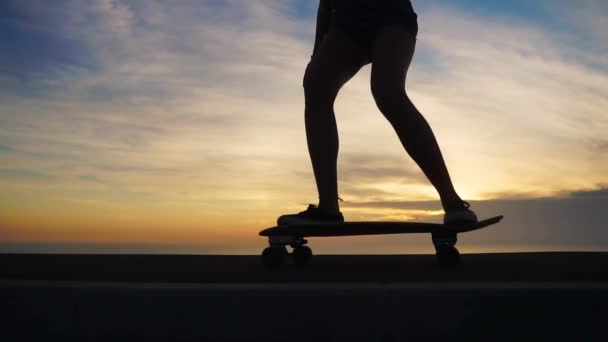 Silhueta de close-up de skates contra o céu por do sol em câmera lenta. Pés com skate close-up . — Vídeo de Stock