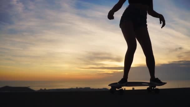 Silhouet van een skateboarder tegen het avondrood in slowmotion steadicam schot — Stockvideo