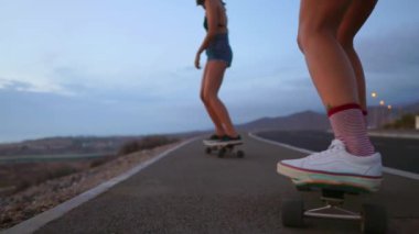 Yakın - up bir kaykay ve iki kız kurullarında üzerinden bir dağ kayalar ve gökyüzü bir arka plan üzerinde sürme vardır. Ağır çekim steadicam