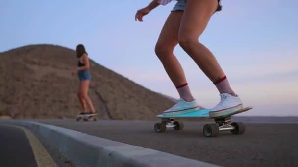 Twee meisjes skateboarder ritten op een bord op de helling tegen de hemel van de berg. Slow motion steadicam — Stockvideo