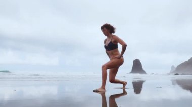 Okyanus sırayla her bacak kayalar ve su arka planı lunges performans spor için bir kadın giriyor