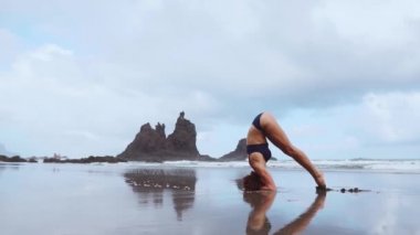 Gün batımında kadın yoga pratik. Yong kadının başı güzel plaj yavaş hareket ile Yoga egzersiz yapması