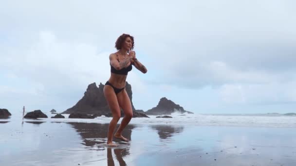 突進を行う海女性エクササイズに沿って岩石と水の背景にそれぞれの脚を交互に。島のリゾートの中に減量のためのトレーニング — ストック動画