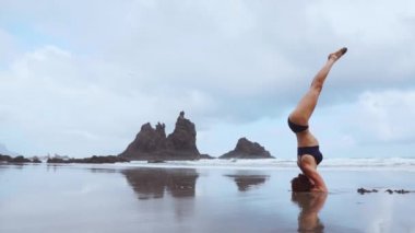 Kafa kızı kumsalda yoga yaparken üzerinde duran