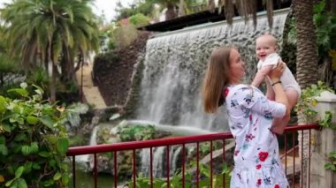 Bir çocukla seyahat, Genç bir anne çalış ve oğlu Şelale sarılarak. Yanaktan öpücük bebek