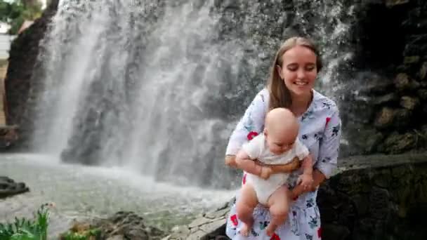 Mutter mit Kind lächelt und umarmt kleinen Sohn über Wasserfall küssen und mit ihm reden. das Konzept einer glücklichen Familie im Urlaub auf den Kanarischen Inseln — Stockvideo