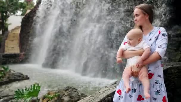 Madre con el niño sonríe y abrazando al bebé hijo sobre la cascada besándose y hablando con él. El concepto de una familia feliz de vacaciones en Canarias — Vídeos de Stock