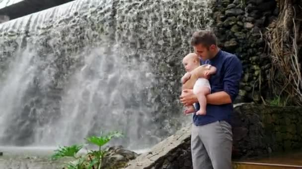 父亲带着孩子微笑着拥抱小儿子, 说瀑布接吻和和和他说话。在加那利群岛度假的幸福家庭的概念 — 图库视频影像