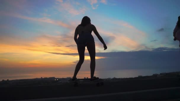 Σιλουέτα skateboarding των δύο κοριτσιών από τον ουρανό και τον ήλιο — Αρχείο Βίντεο
