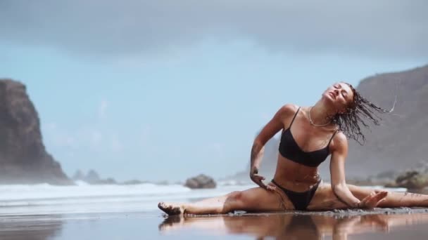 La jeune fille est engagée dans l'étirement et la gymnastique sur le rivage de l'océan . — Video