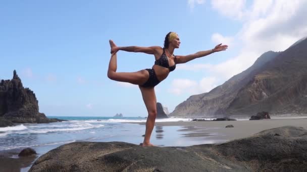 Chica haciendo yoga balanceándose sobre una pierna de pie sobre una piedra. Tranquilidad mental. Estilo de vida saludable — Vídeos de Stock