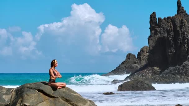 Yoga di meditazione serena. Bruna turista che medita in posizione di loto sul promontorio sopra la panoramica Praia da Marinha. Meditando femmina sulle scogliere delle isole Canarie — Video Stock