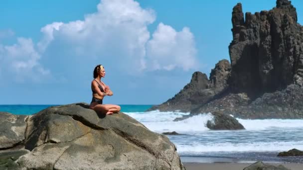 Serene meditation yoga. Brunett turist kvinna mediterar i lotusställning på udde ovanför vackra Praia da Marinha. Mediterar kvinna på klipporna över Kanarieöarna — Stockvideo