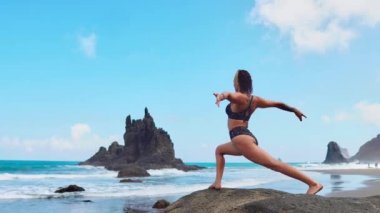 yoga poz lotus kayaların üzerinde çalışan okyanus dalgaları karşı mor mat siyah top sarışın kız rahatlatır