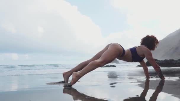 Fitness-Frau Krafttraining mit klassischer traditioneller Ellenbogenplanke, auch Unterarmplanke genannt. Mädchen trainieren Körperkernmuskeln und Bauchmuskeln. Sportler planken Training im Freien am Strand. — Stockvideo