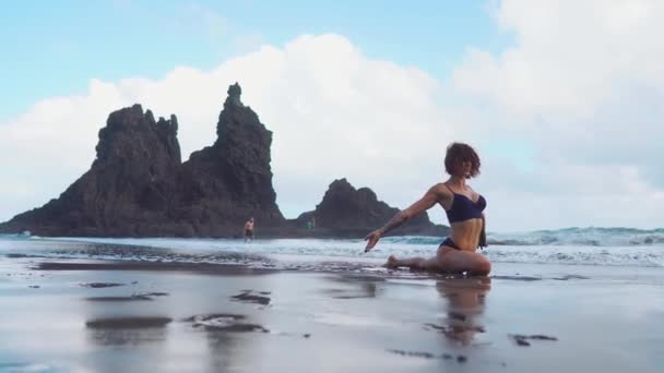 Fitness lány vagy fiatal nő alakzat sziluettje, szörfös csinál néhány nyújtó exersices, homokos strandon, torna. clolrful ég, nyugodt tenger, vagy óceán, horizont, homokos strandon, vagy partján, mint háttér — Stock videók