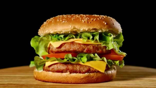 Verse, smakelijke hamburger draaien op zwarte achtergrond. Seamless loopbare geschoten, 4k. — Stockvideo