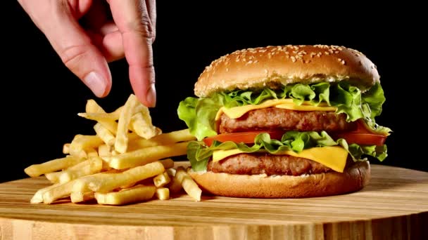 クラフト牛肉のハンバーガーとフライド ポテト、黒い背景に分離されたソース。ファーストフード — ストック動画