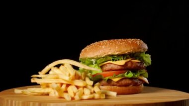 Zanaat sığır eti hamburger ve patates kızartması siyah arka plan üzerine izole ahşap tablo.