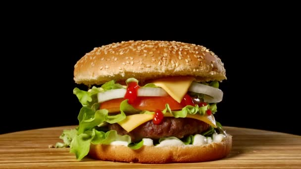 Cheesburger se slaninou na tmavém pozadí. Detail. Makro fotografování.