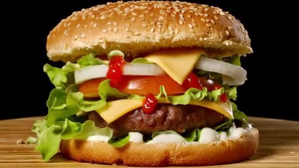 Na malé dřevěné prkénko podává detailní domácí hovězí hamburger s hlávkovým salátem a majonézou. Tmavé pozadí — Stock video
