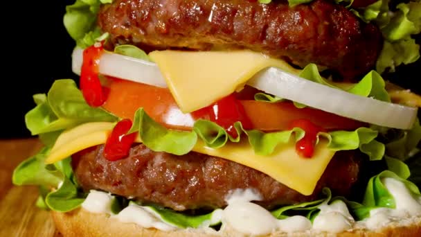 Closeup of home made beef burgers with lettuce and mayonnaise served on little wooden cutting board. Dark background — Stock Video